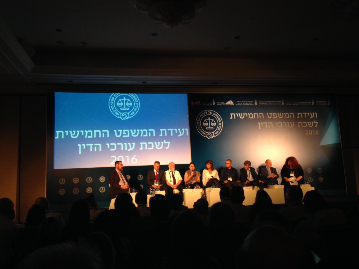 Panel of 9 speakers before a live audience. Background text: "5th Legal Conference, Israel Bar, 2016."